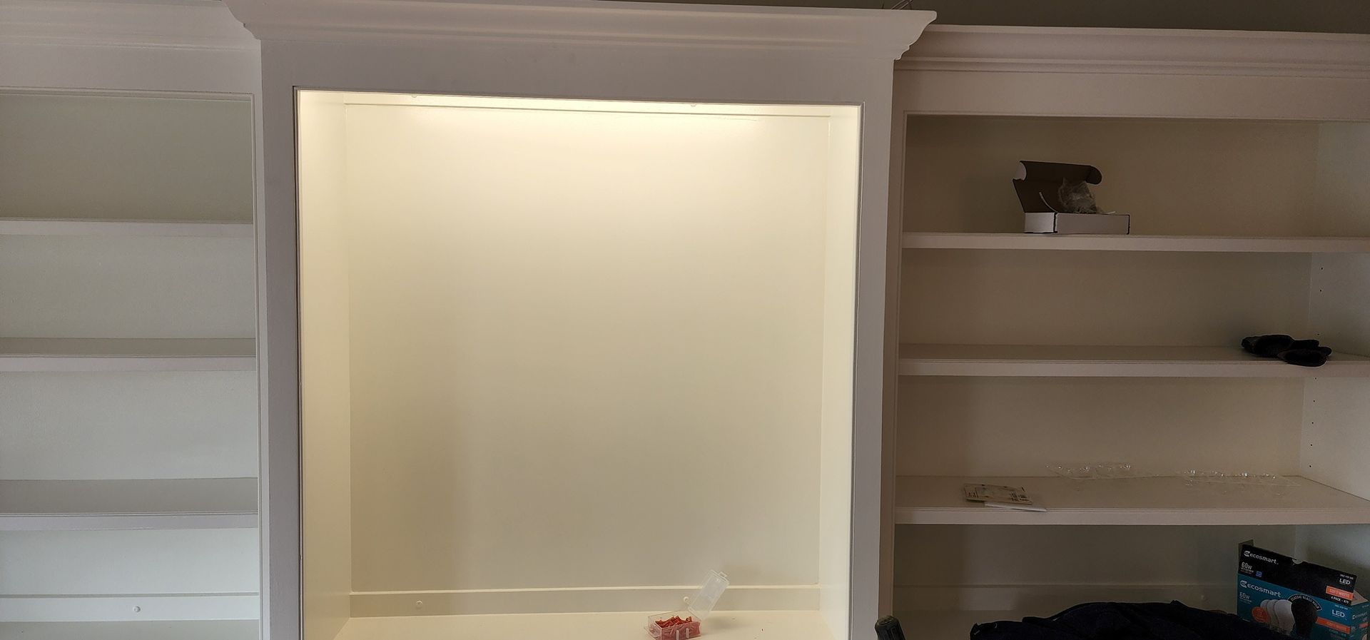 A room with a lot of shelves and a window.