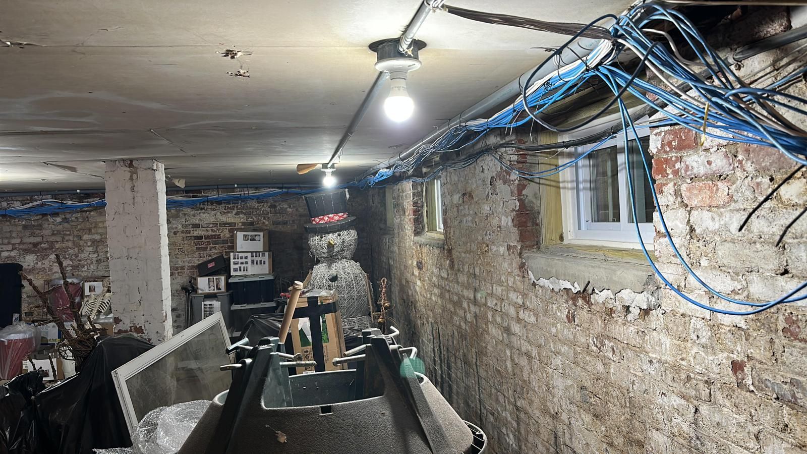 A basement with a lot of wires hanging from the ceiling.