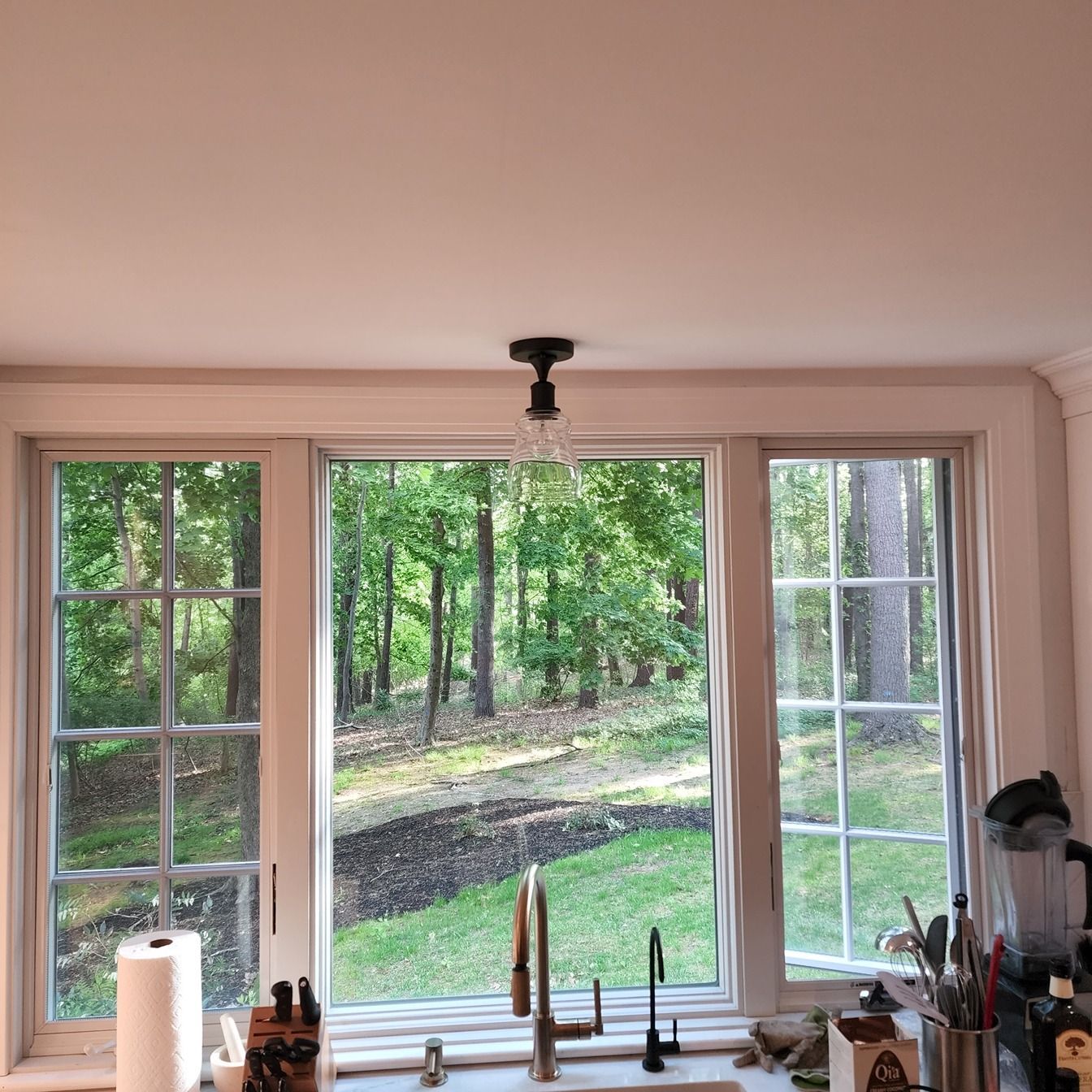 A kitchen with a sink and a window with a view of the woods.