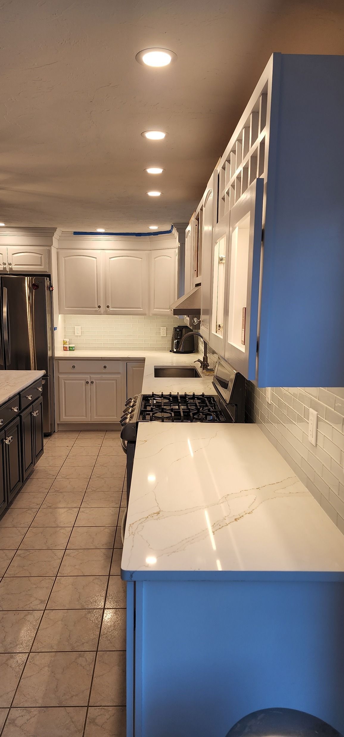 A kitchen with blue cabinets and white counter tops.