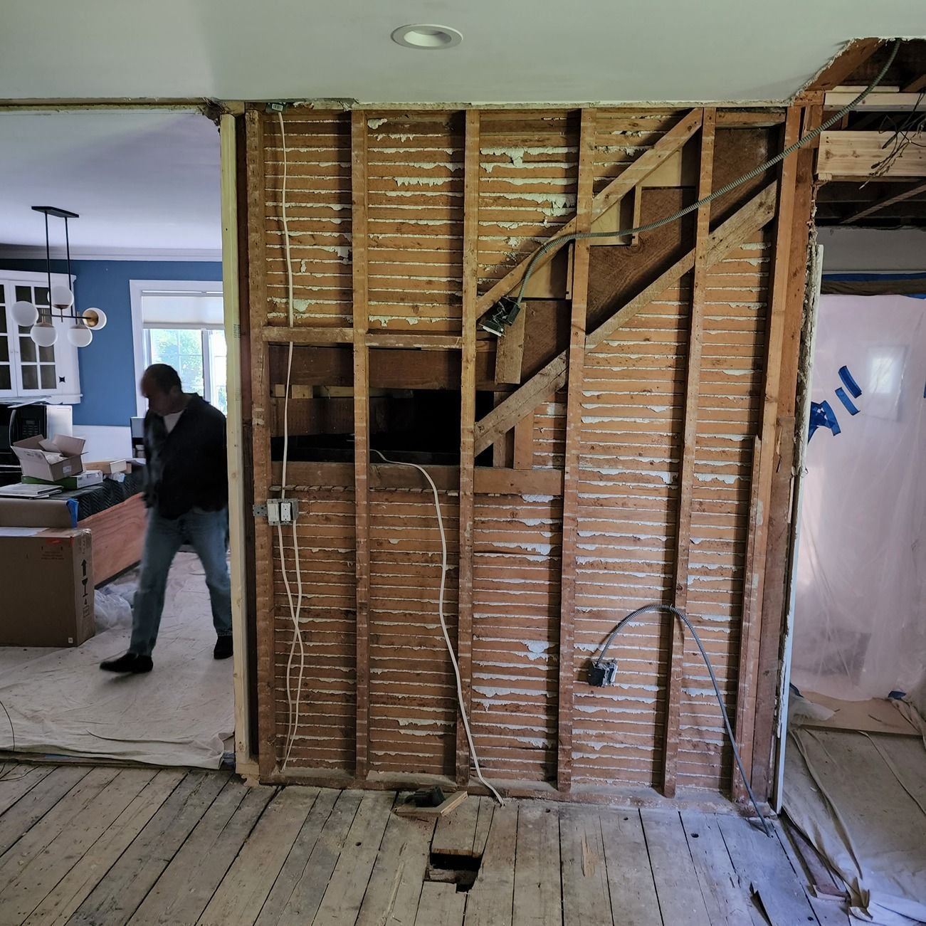 A man is standing in a room with a brick wall and stairs.