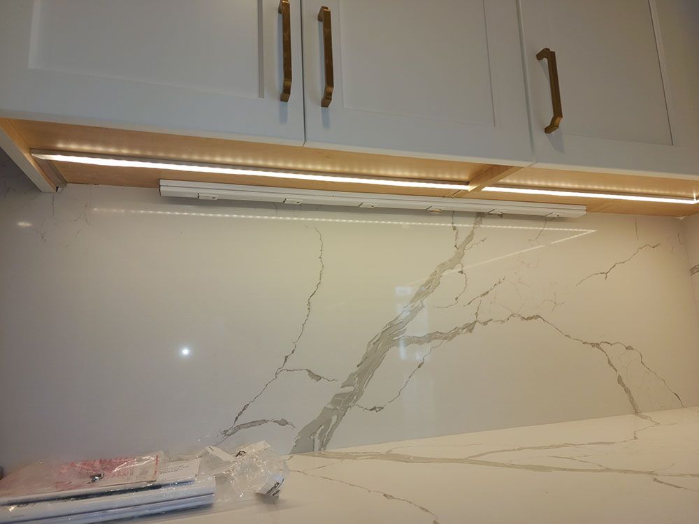 A kitchen with white cabinets and a marble counter top.