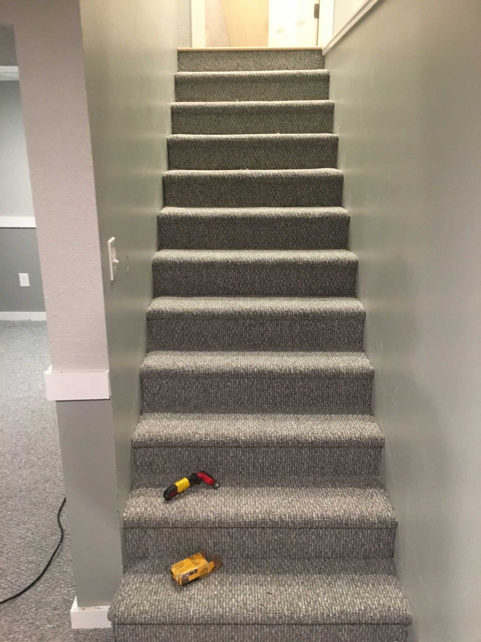 Carpeted staircase with gray walls, toys on stairs, and a door at the top.