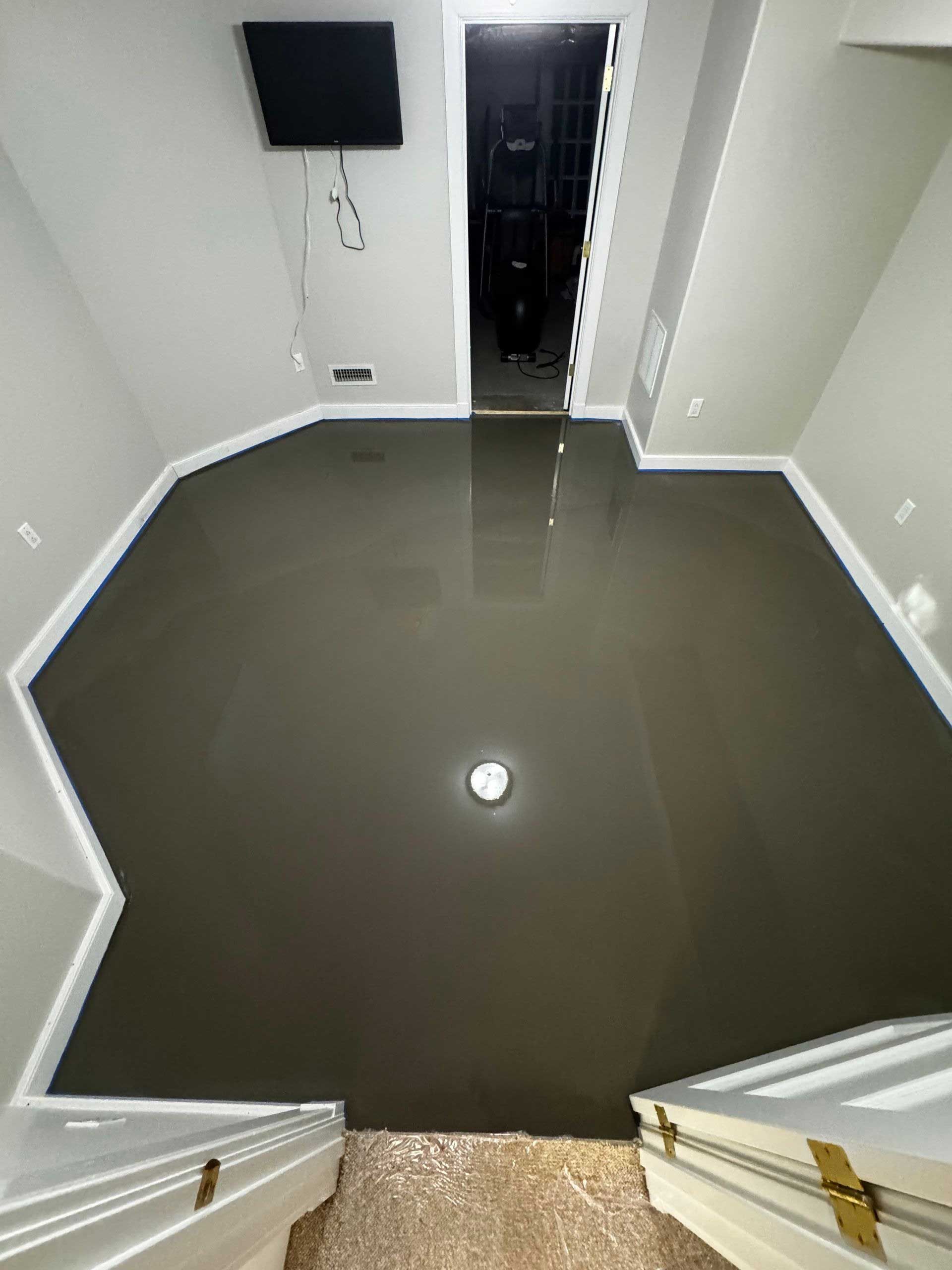 Gray floor with a shiny surface, white trim, and a dark hallway in the background.