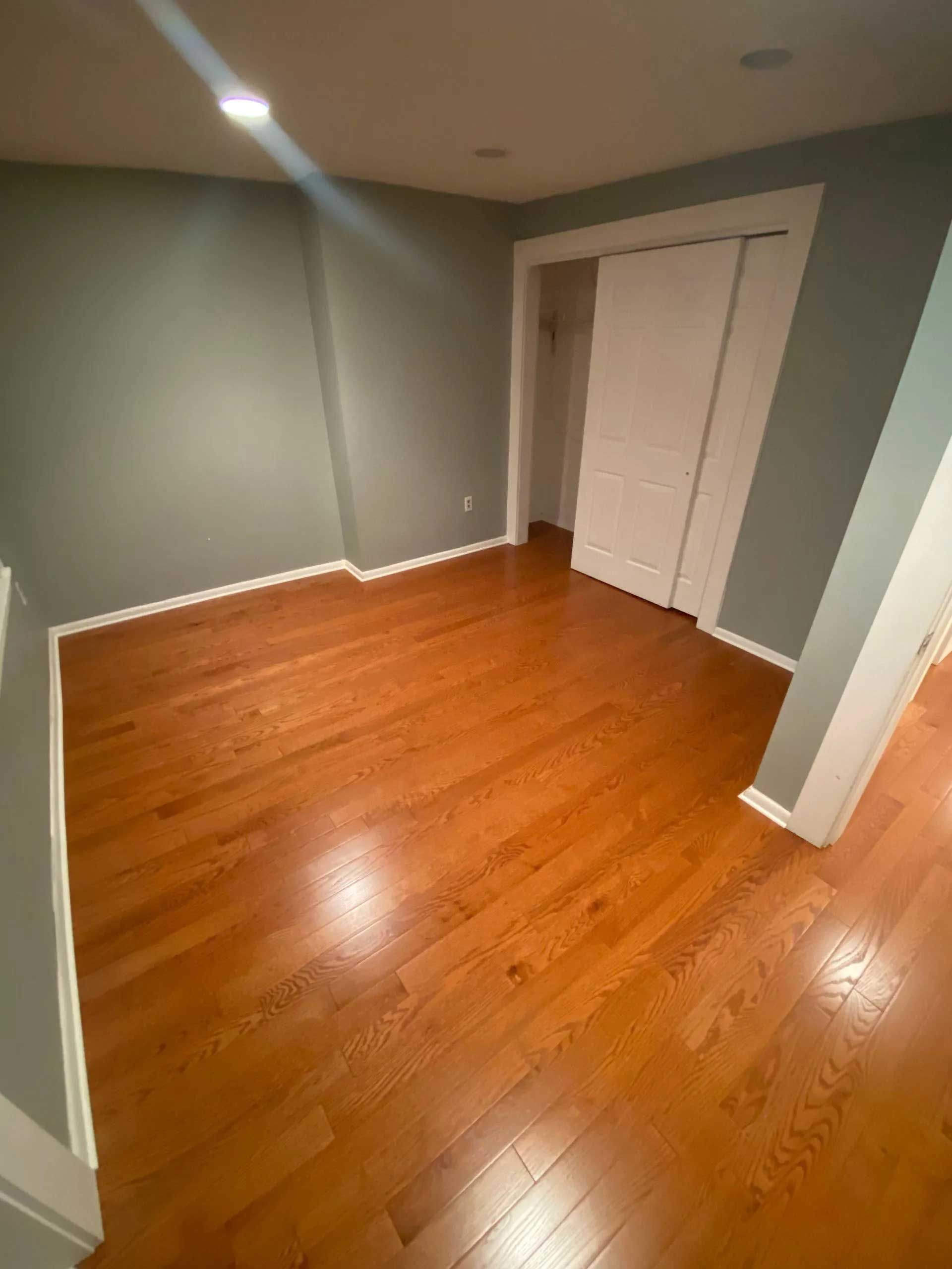 Room with hardwood floor, gray walls, and white trim, door.