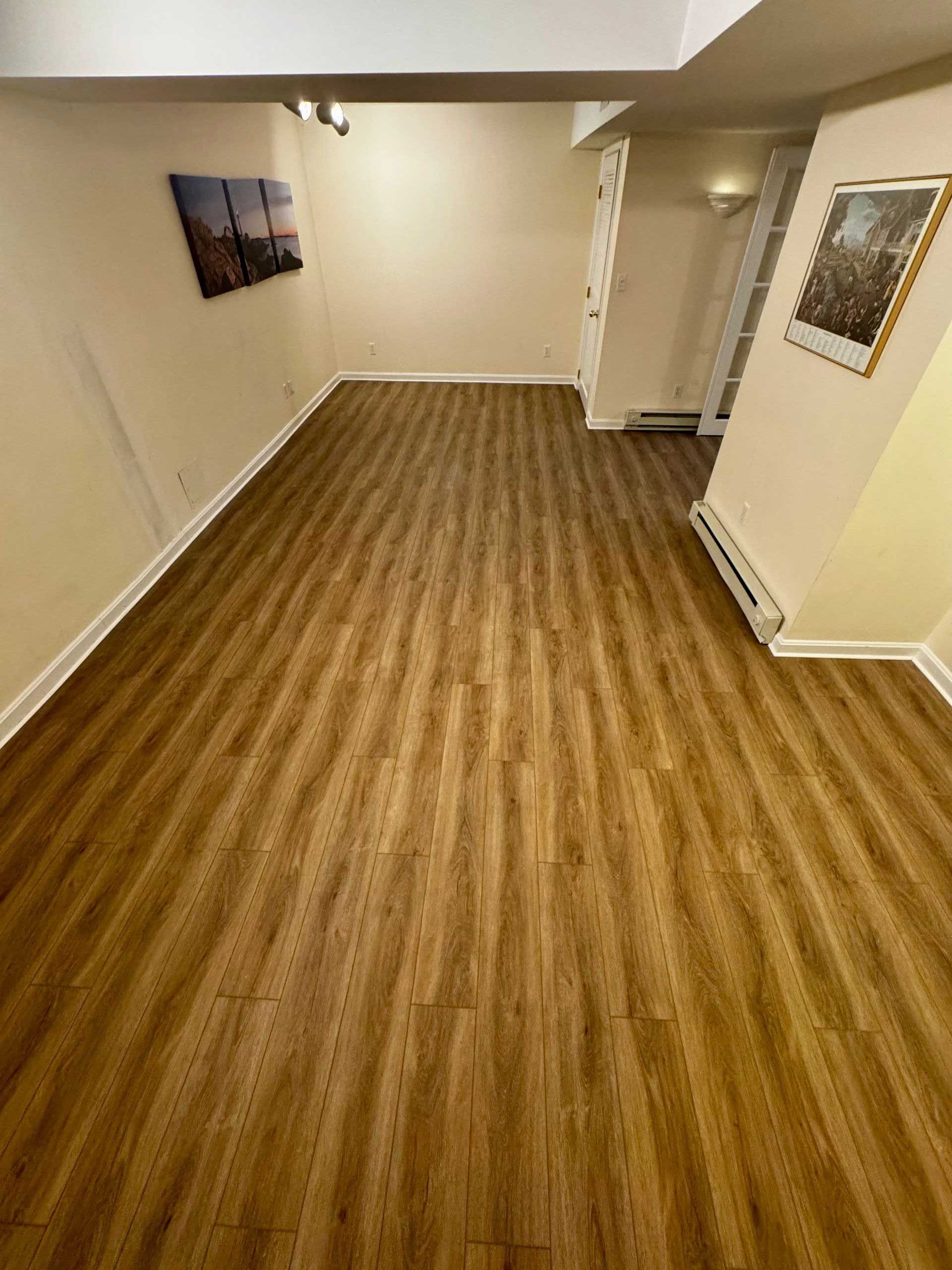 Wooden-floored room, neutral walls, art pieces, and a door frame.