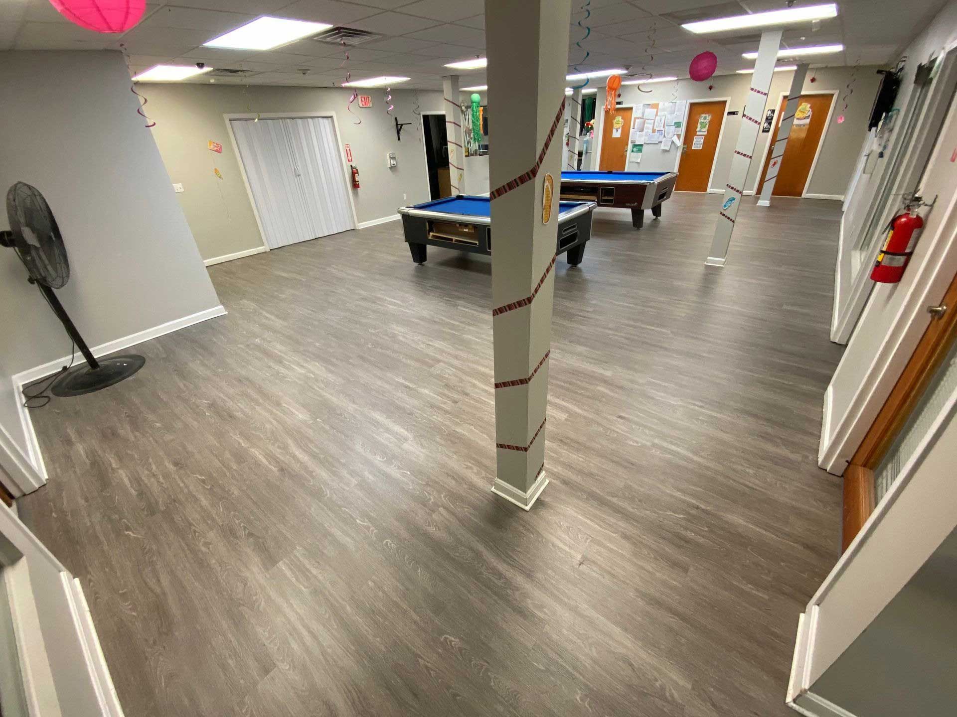 Game room with pool tables, gray floors, and a decorative column.