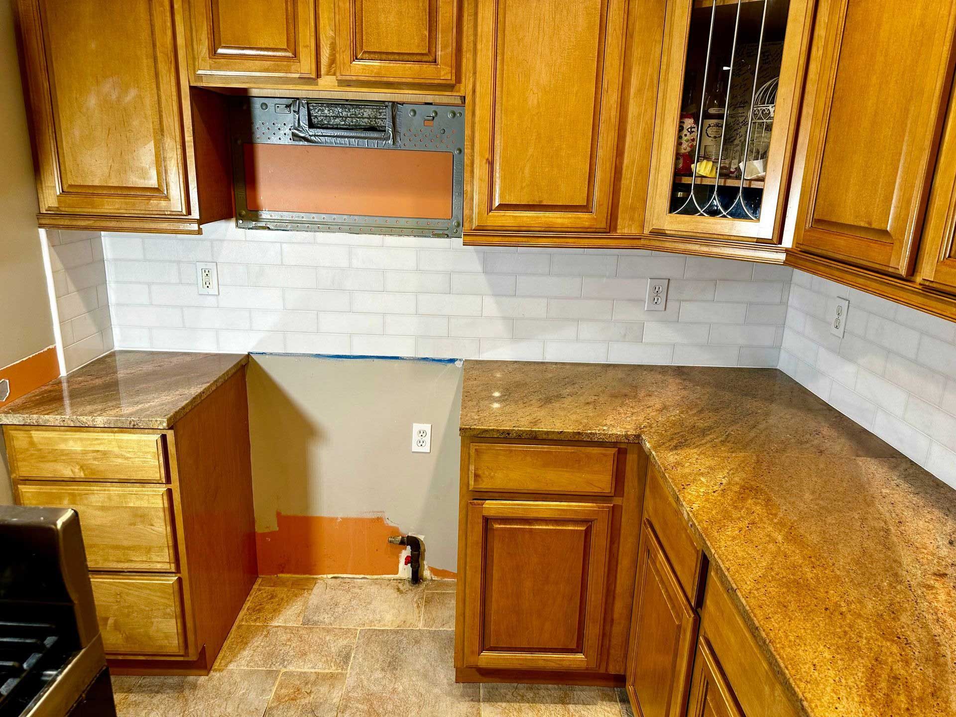 Kitchen with brown cabinets, granite countertops, and white subway tile backsplash.