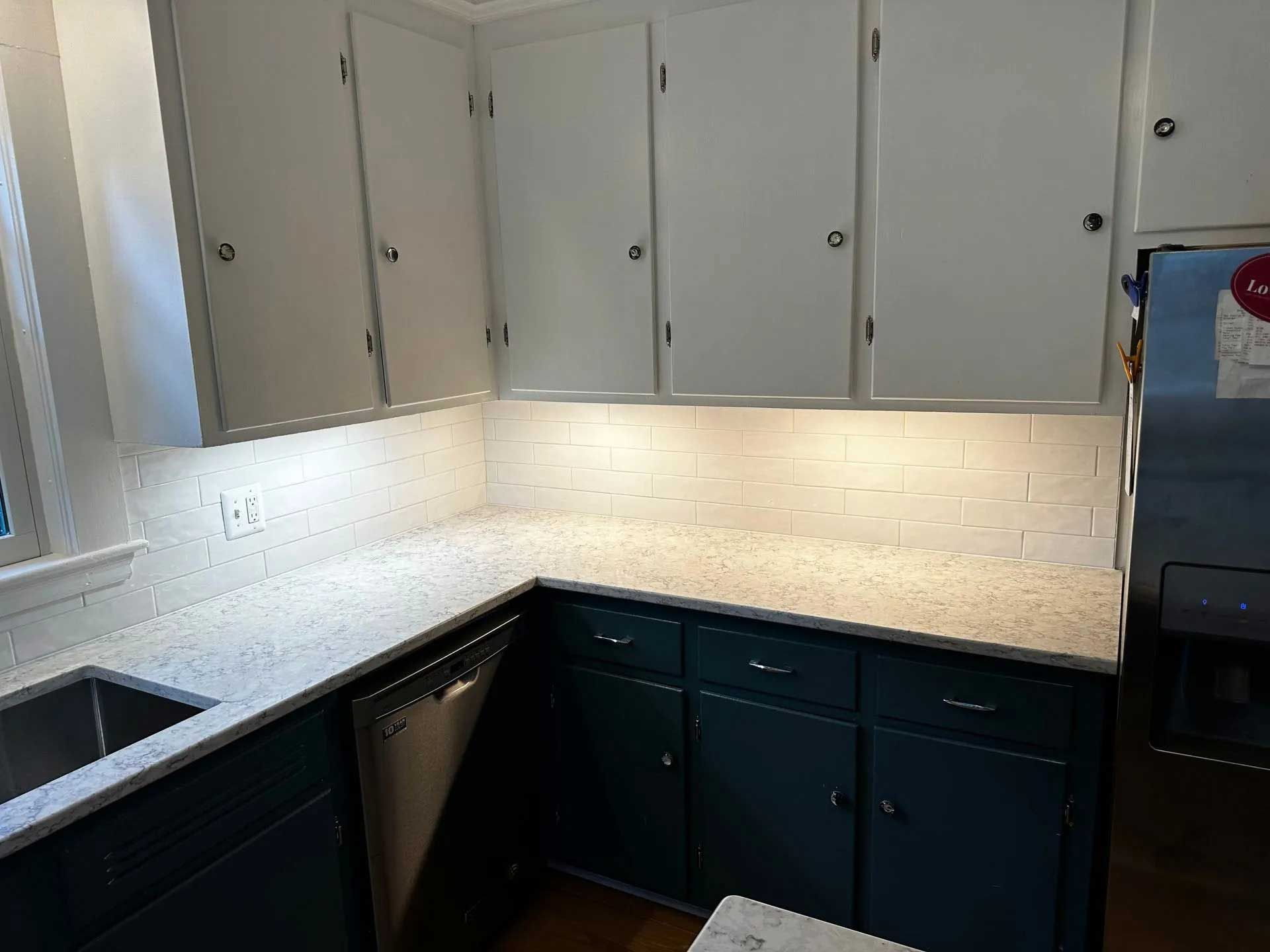 Kitchen with white upper cabinets, teal lower cabinets, and a white countertop.