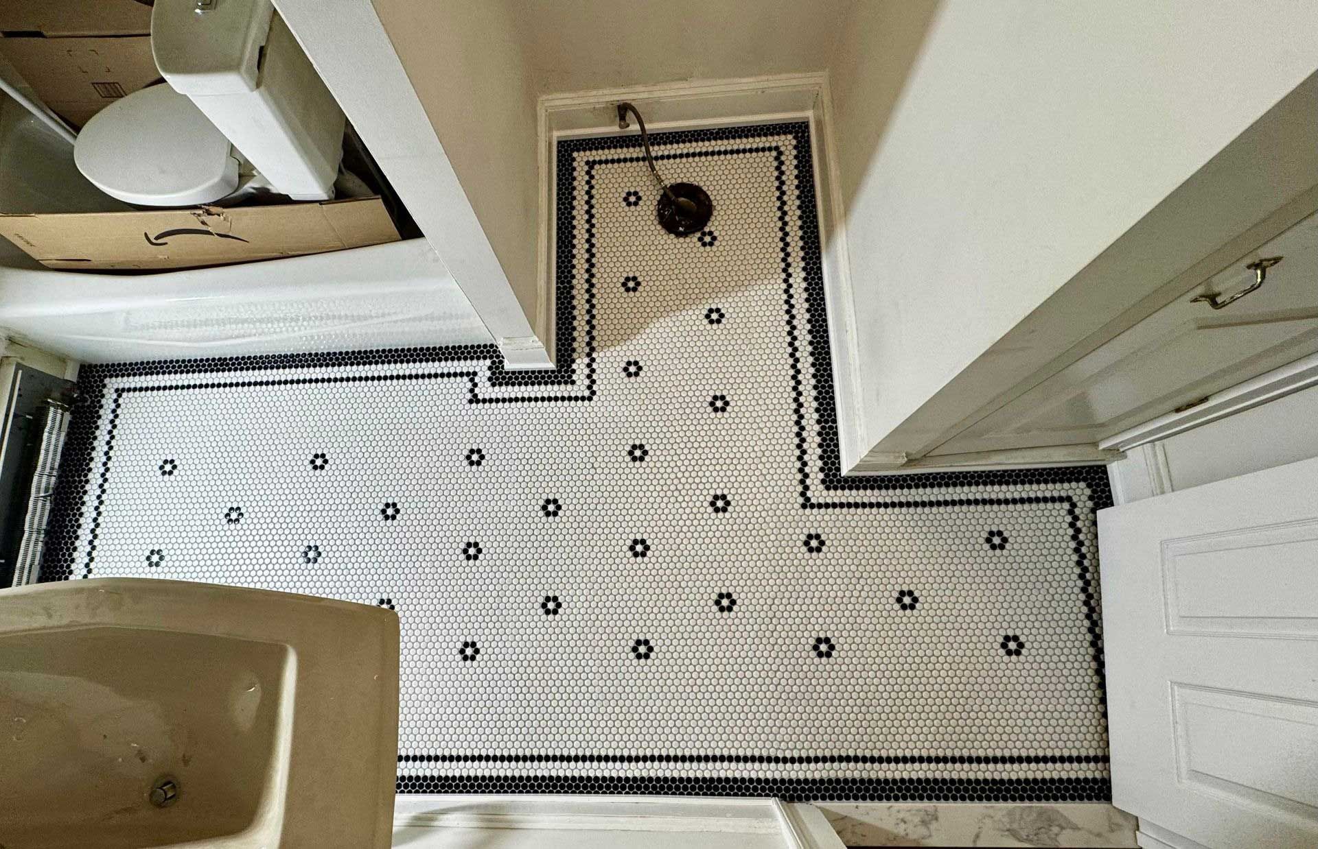 Bathroom with white and black patterned tile floor, toilet, sink, and door.