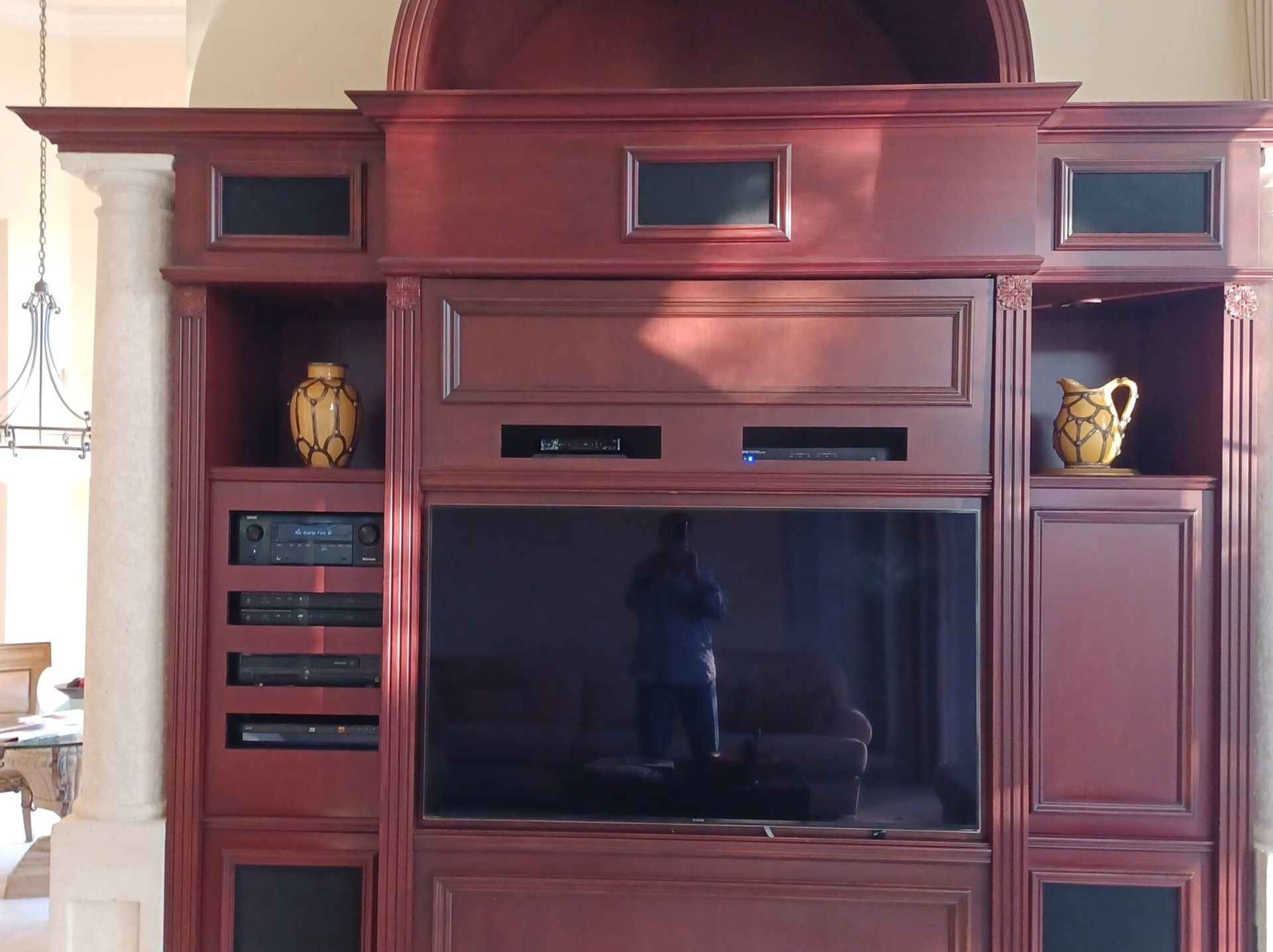 Dark wood entertainment center with TV, shelves, and decorative vases in a living room.