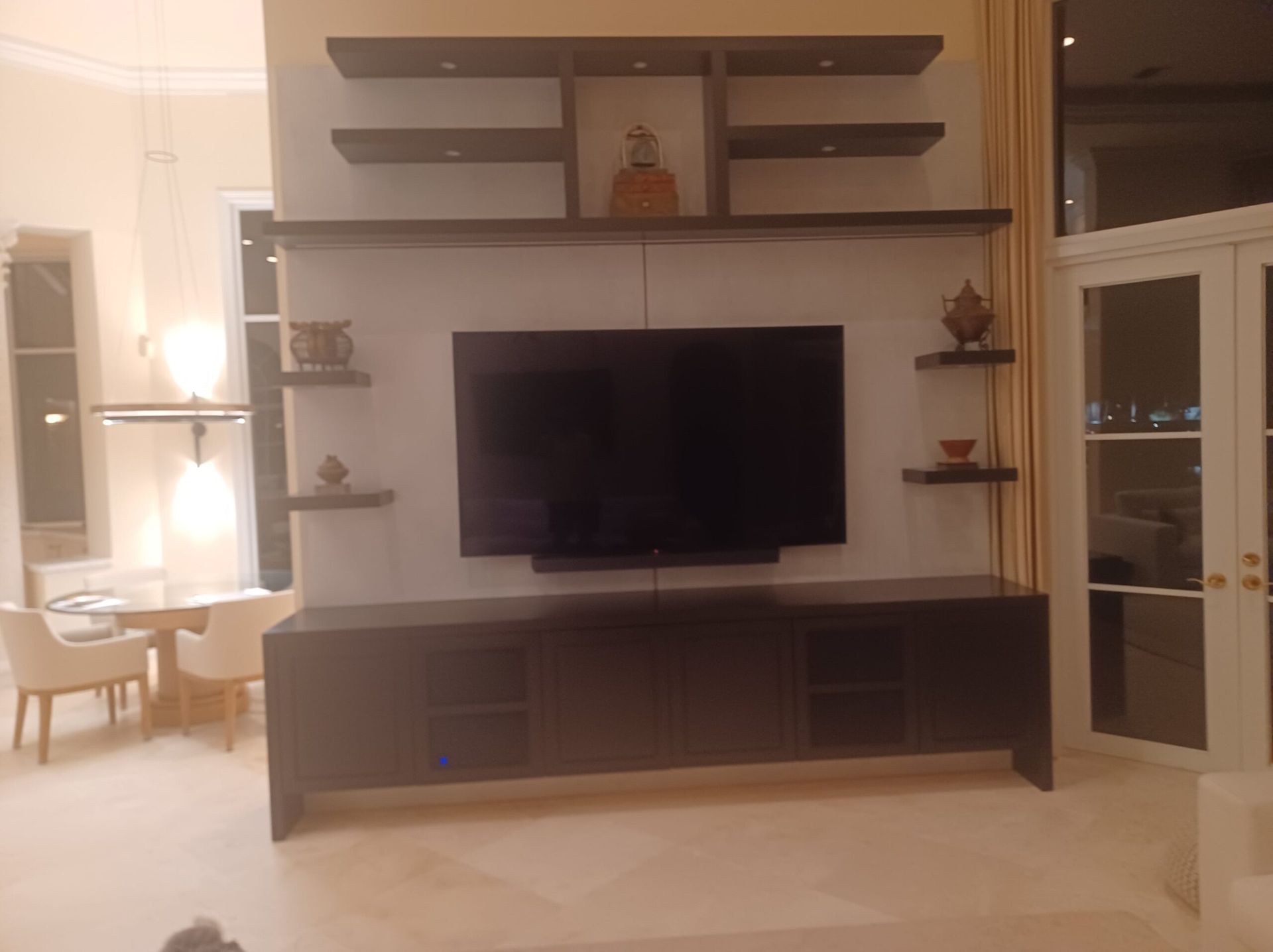Living room wall unit with mounted TV, shelves, and dark wood cabinetry