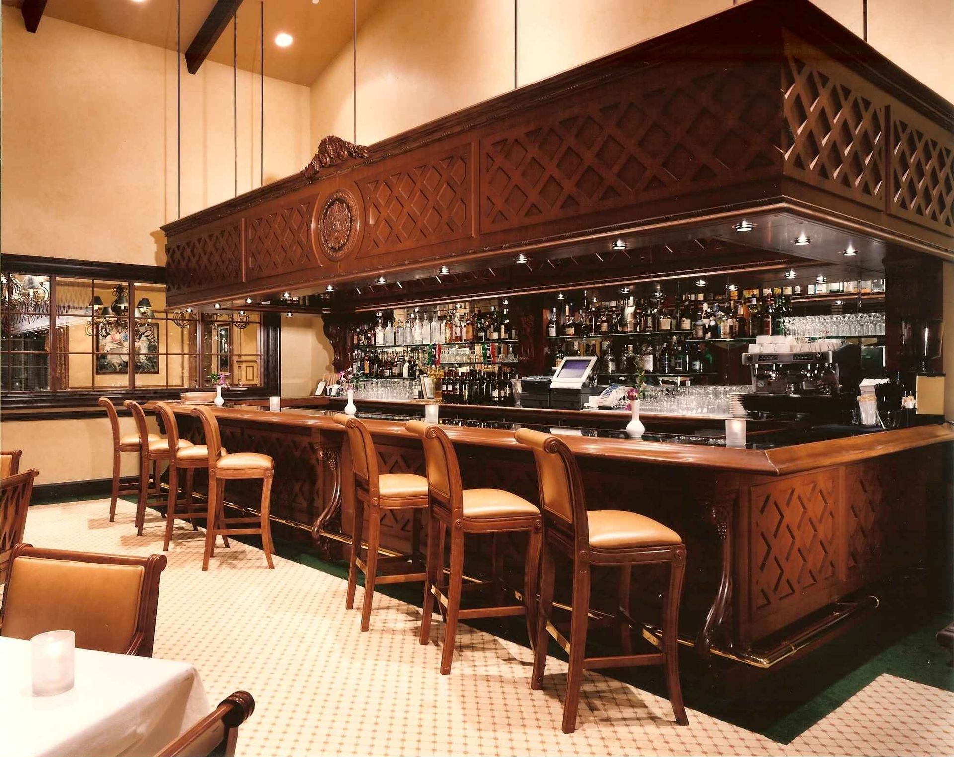 Warm wood-paneled bar with stools, mirrors, and an empty counter in a softly lit restaurant interior