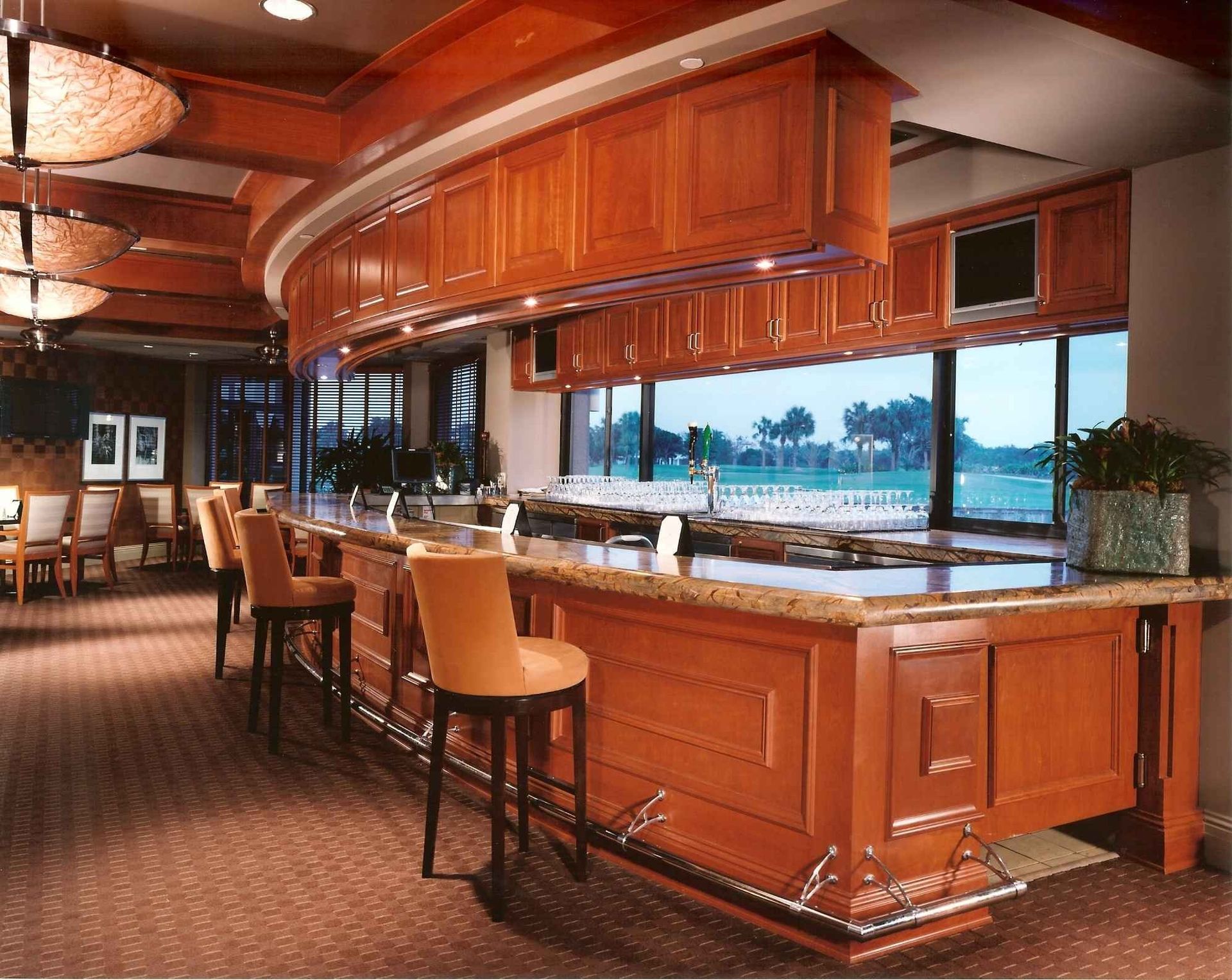 Luxurious wood-paneled bar with stools and a waterfront view through large windows