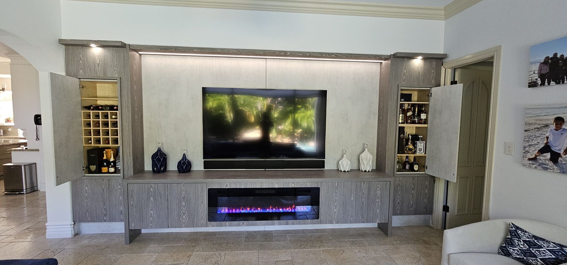 Modern living room with a wall-mounted TV above a linear electric fireplace and built-in shelves