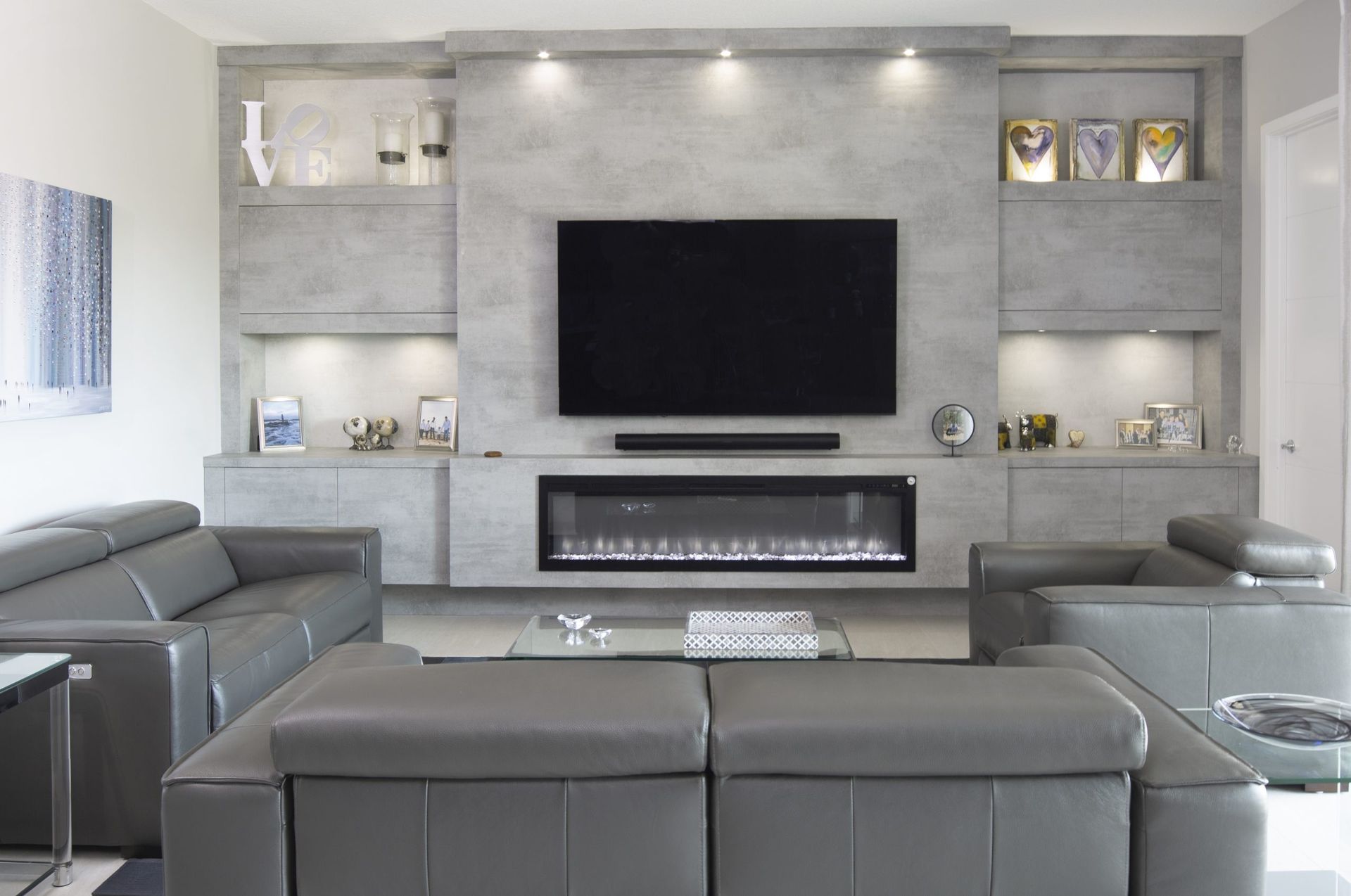 Modern gray living room with built-in shelves, wall-mounted TV, fireplace, and sectional sofas