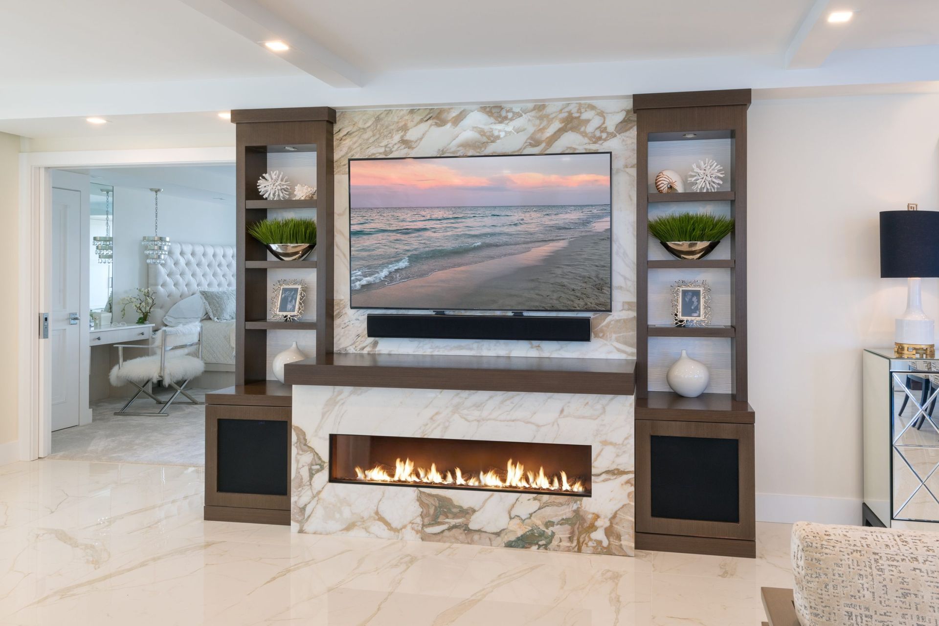 Modern living room with wall-mounted TV above a fireplace and built-in shelves, in bright neutral tones
