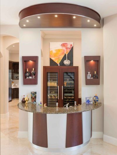 Built-in bar nook with granite countertop, wine cooler, glassware, and warm recessed lighting