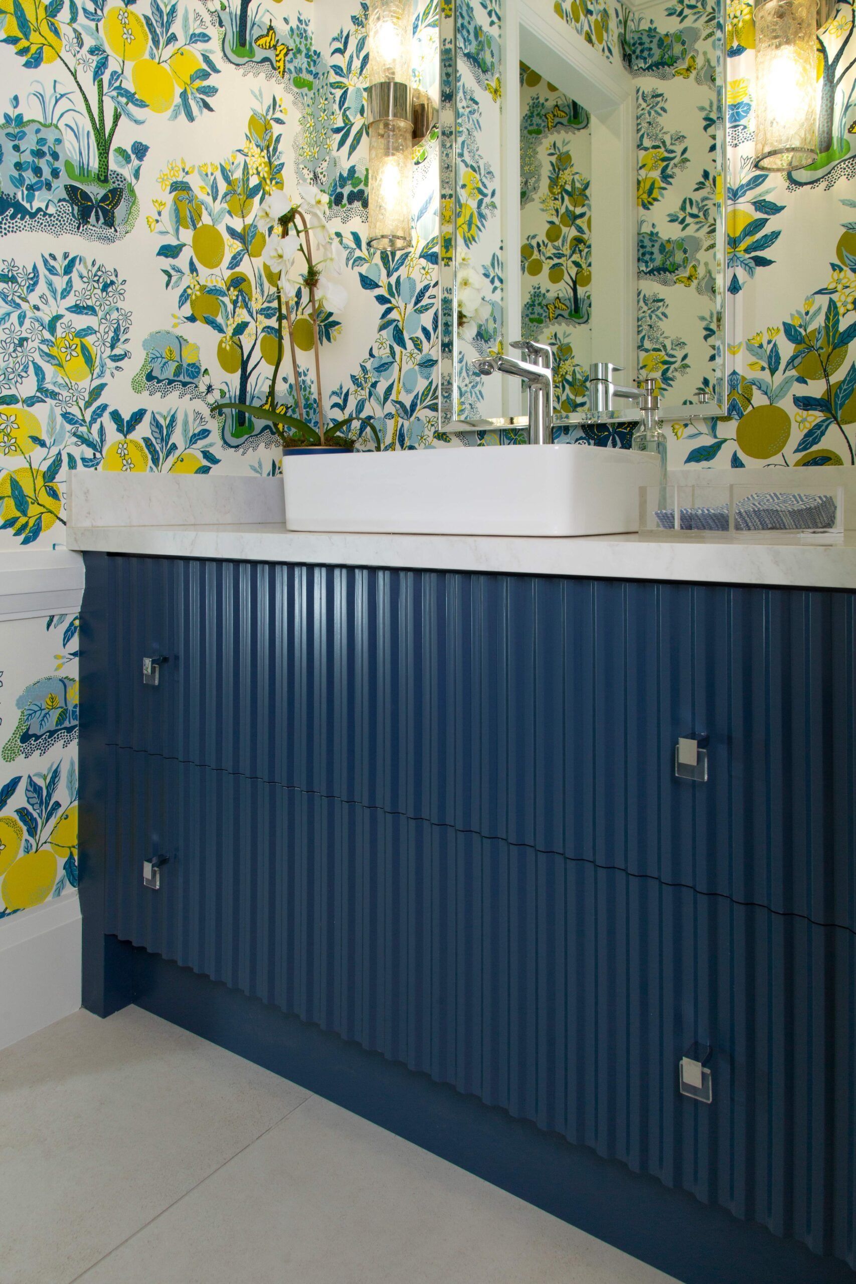 Blue vanity with white sink and floral wallpaper in a bright bathroom