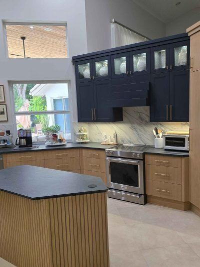 Modern kitchen with navy cabinets, stainless appliances, and a dark island countertop