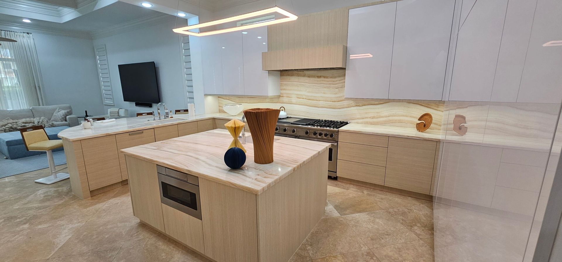 Bright white kitchen with a large island, cabinets, and decorative vases under pendant lights