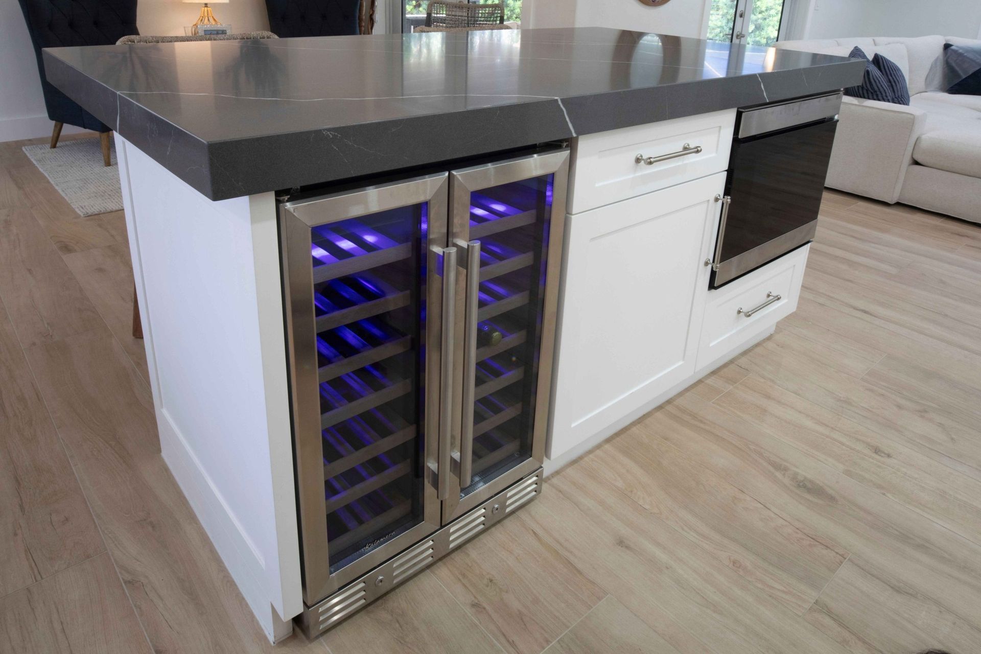 Modern kitchen island with built-in blue-lit wine coolers and a black countertop