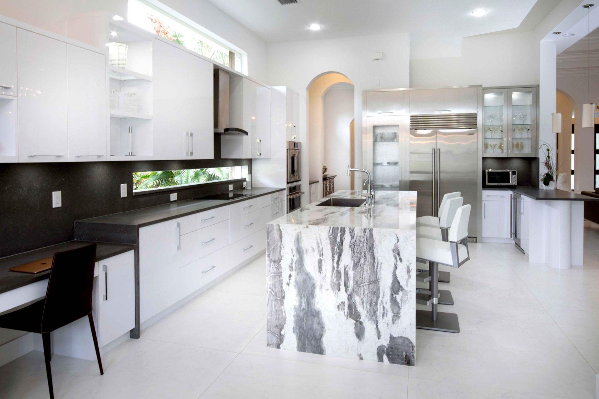 Modern white kitchen with marble island, black countertops, and stainless steel appliances