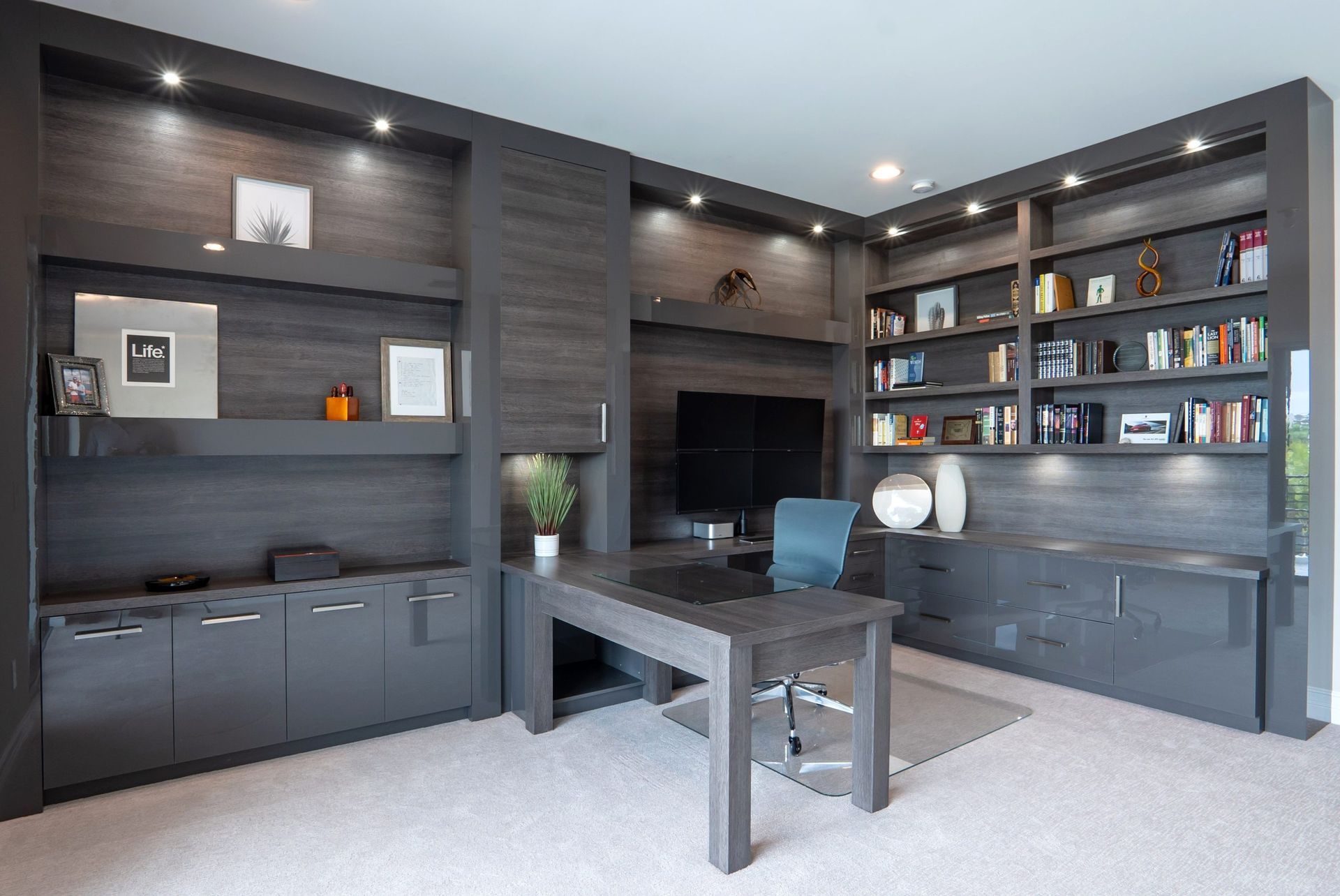 Modern home office with dark wood built-ins, desk, shelves, and recessed lighting