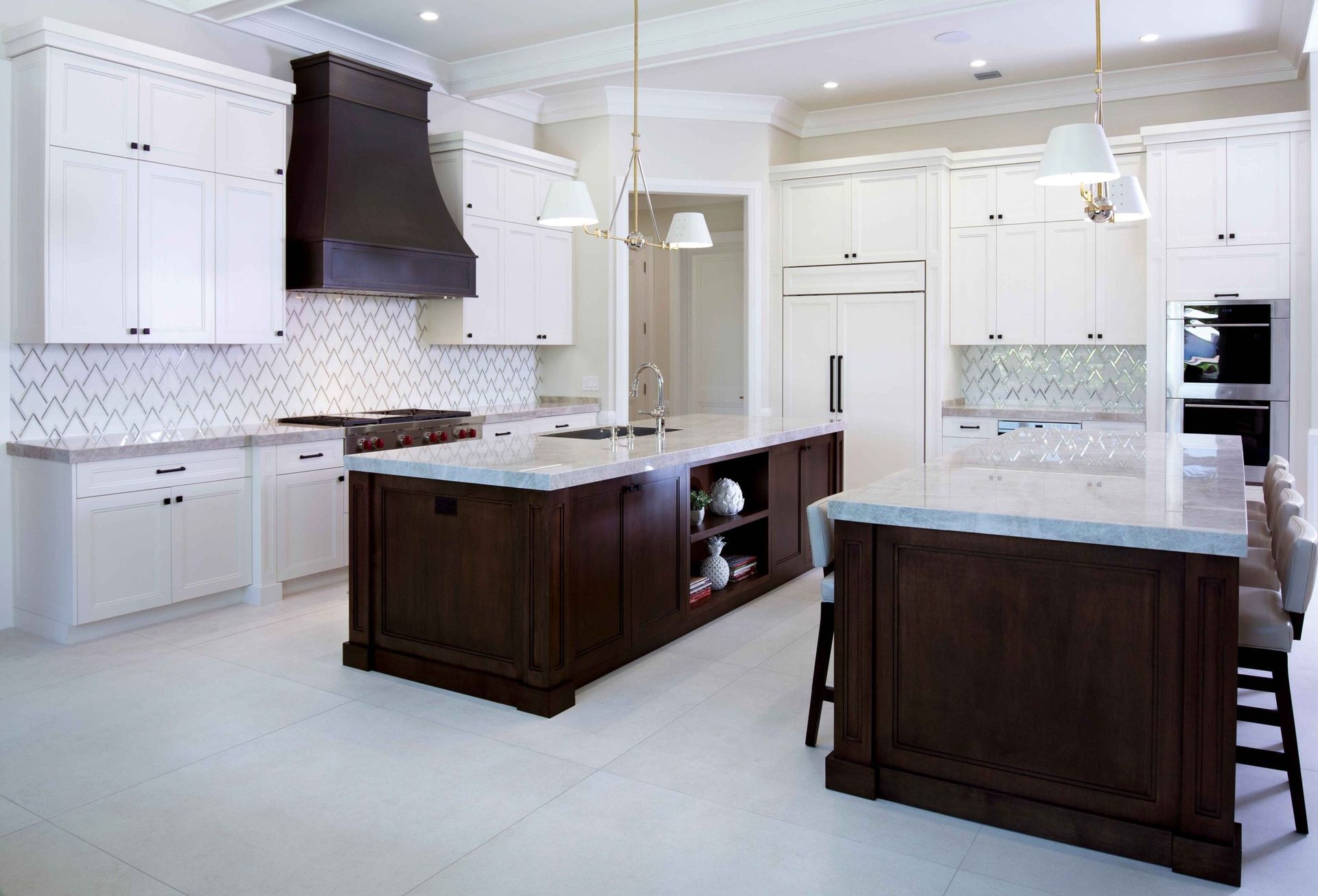 Bright modern kitchen with white cabinets, dark wood islands, and pendant lights