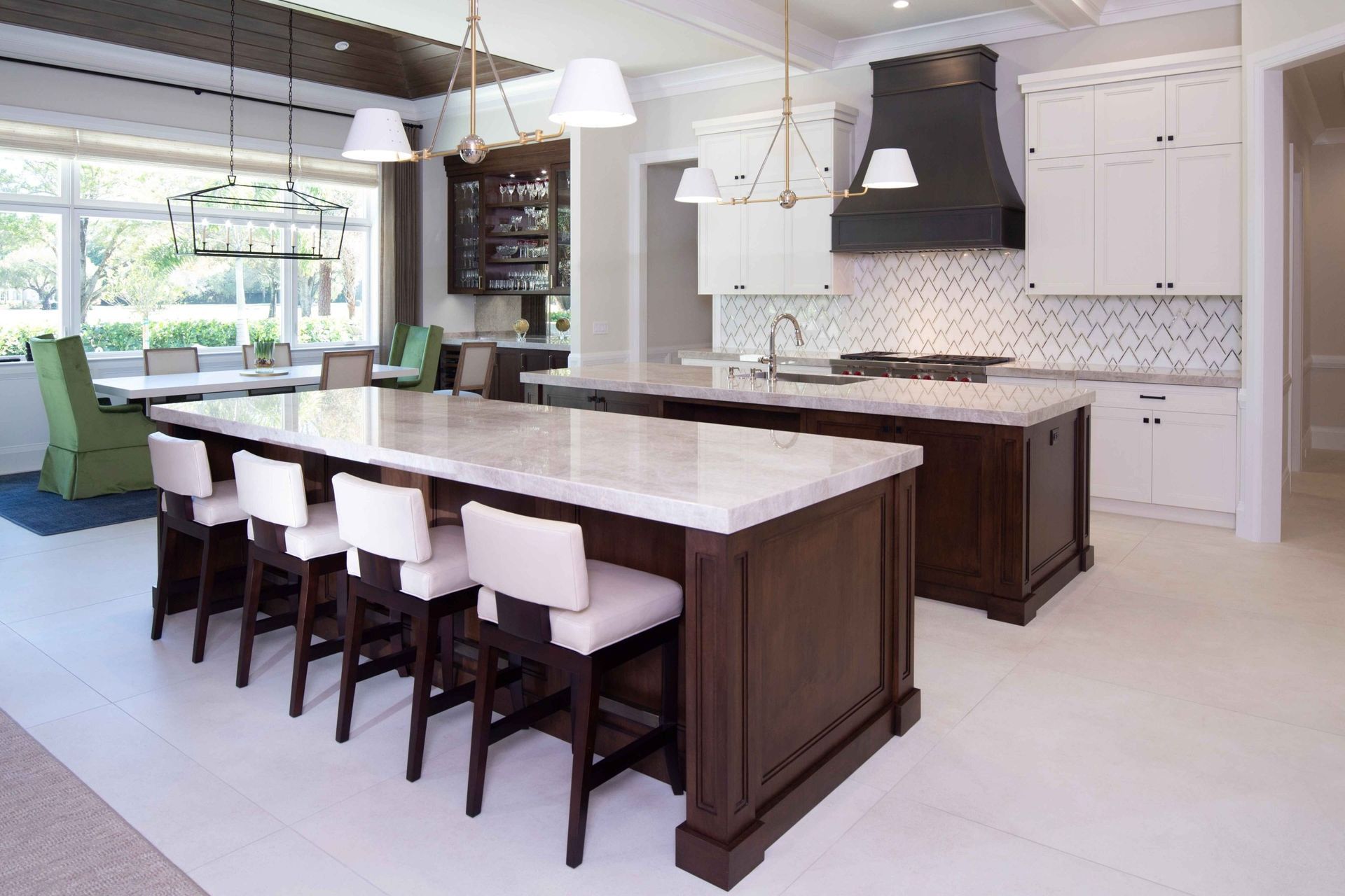 Modern kitchen with a large island, white cabinets, and bar stools beside a bright dining nook