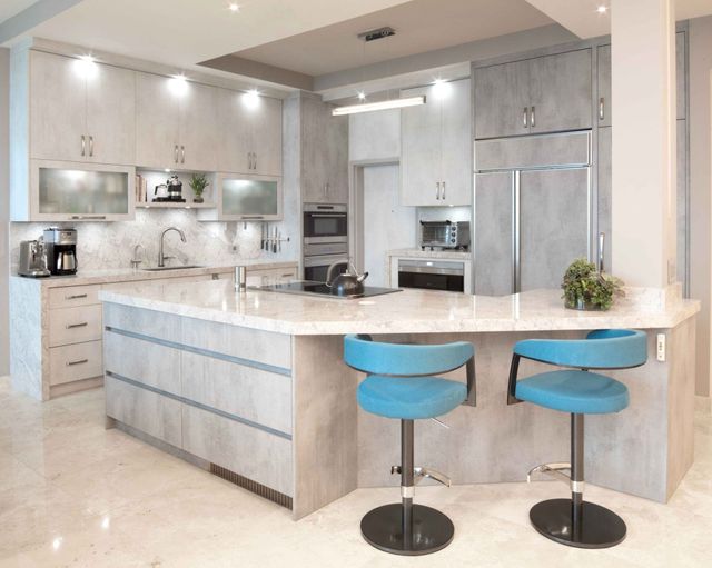 Bright modern kitchen with light wood cabinets, marble island, and two blue bar stools