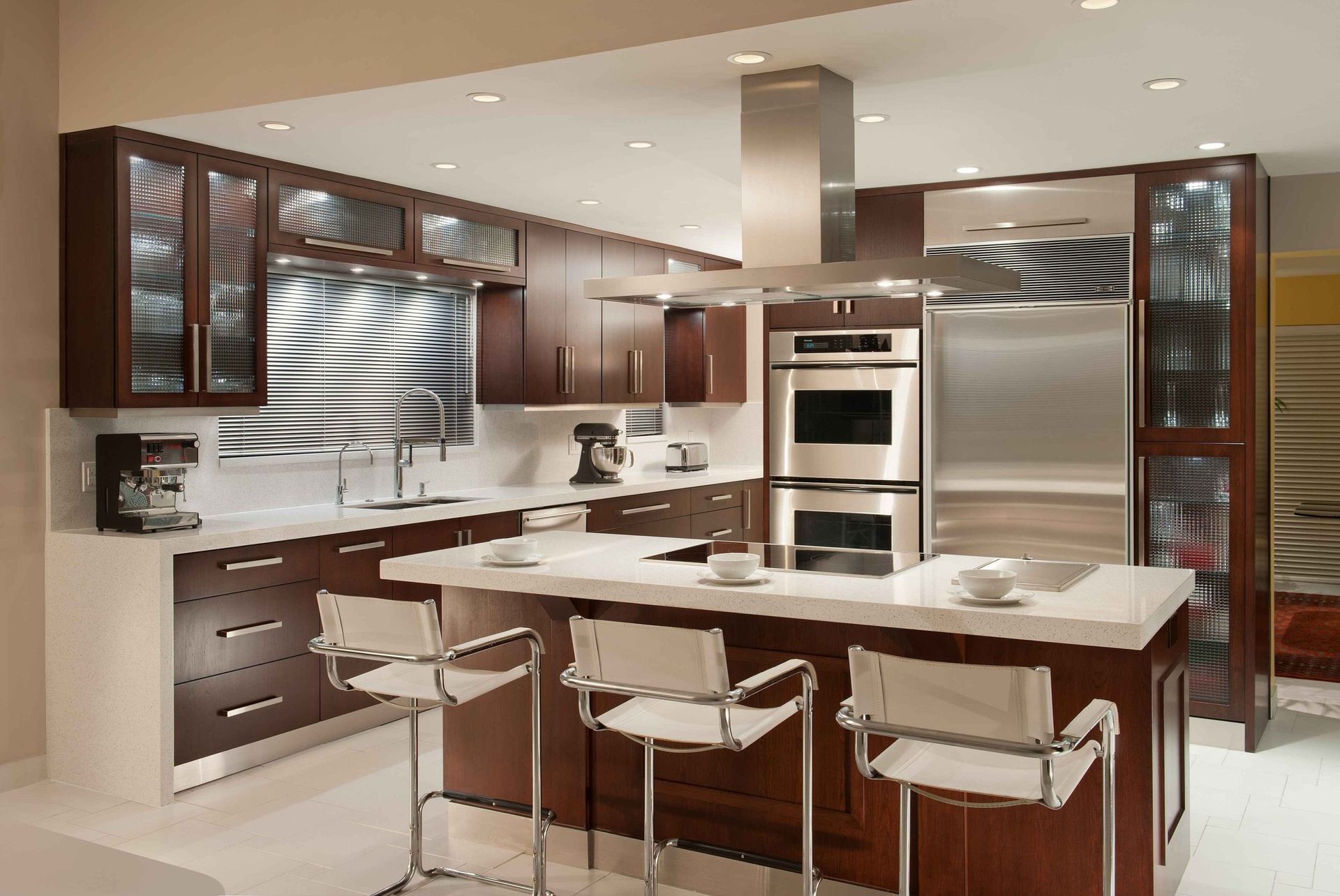 Modern kitchen with dark wood cabinets, stainless appliances, white island, and four bar stools