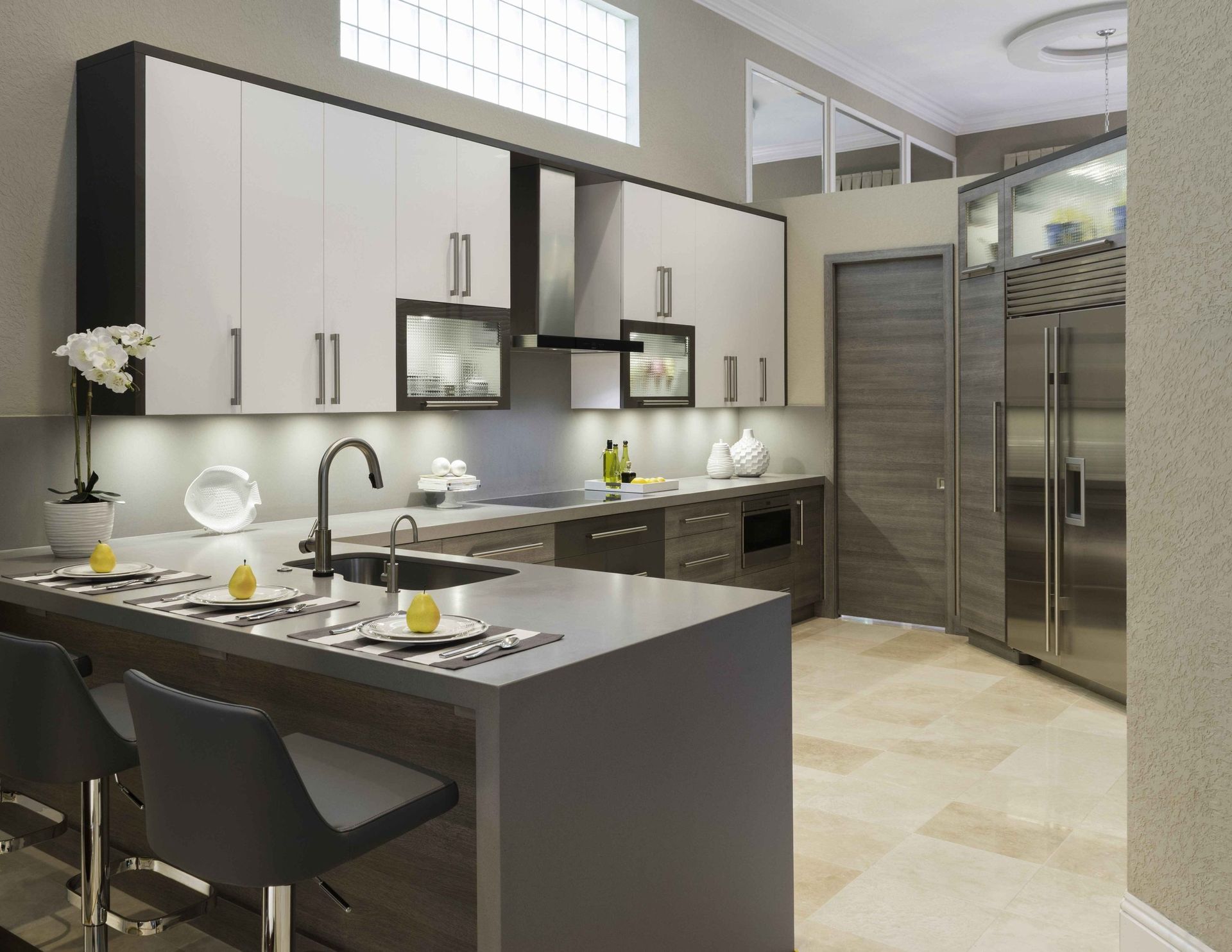 Modern kitchen with gray island, white cabinets, black stools, and stainless steel appliances