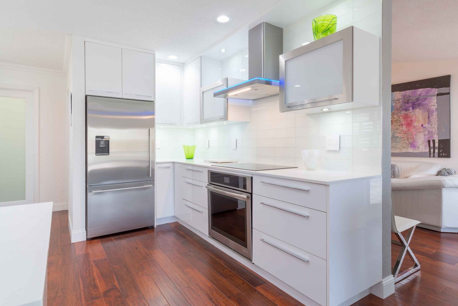 Modern white kitchen with stainless steel appliances and hardwood floors