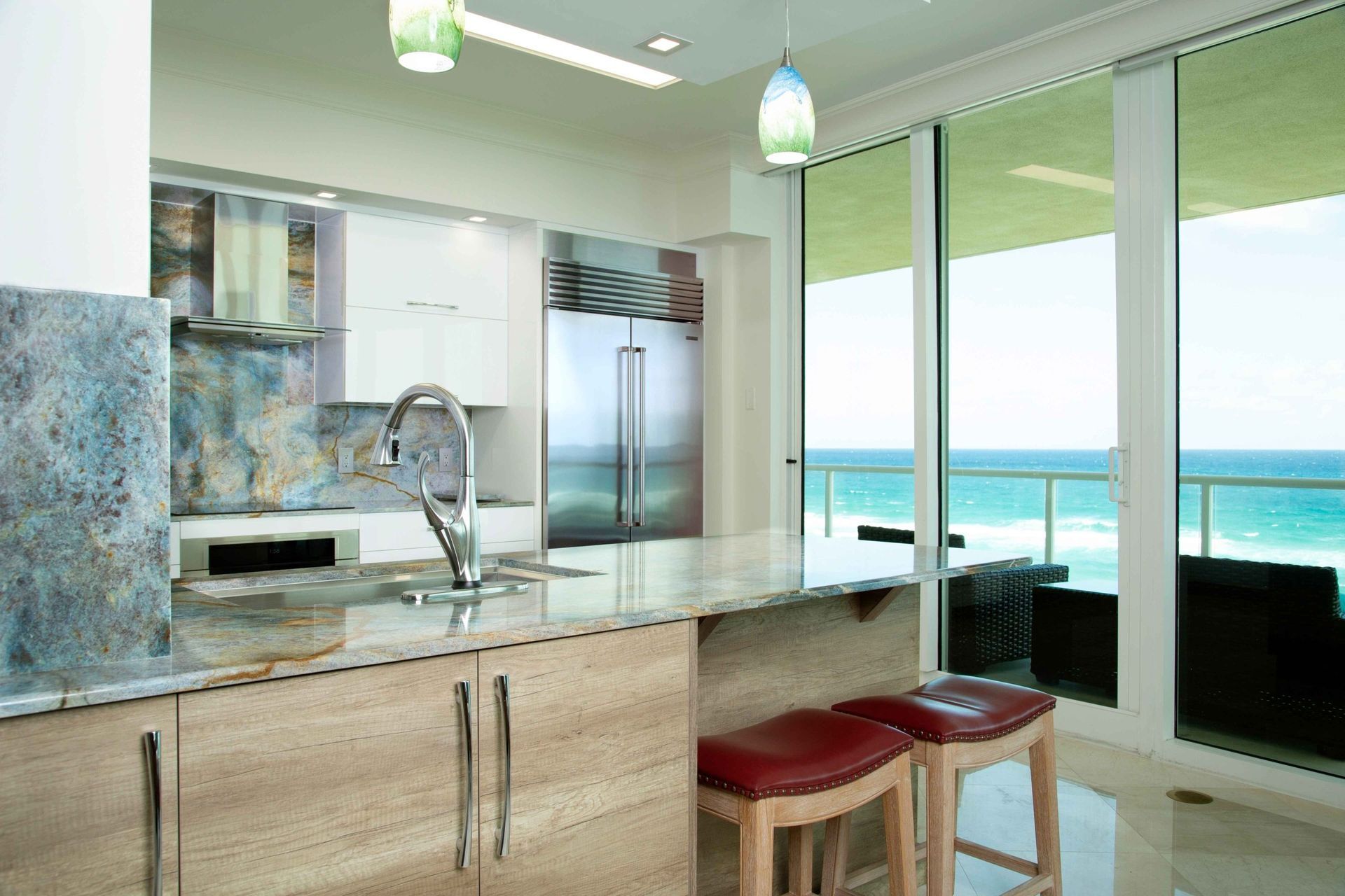 Modern kitchen with island, red stools, and ocean view through large windows