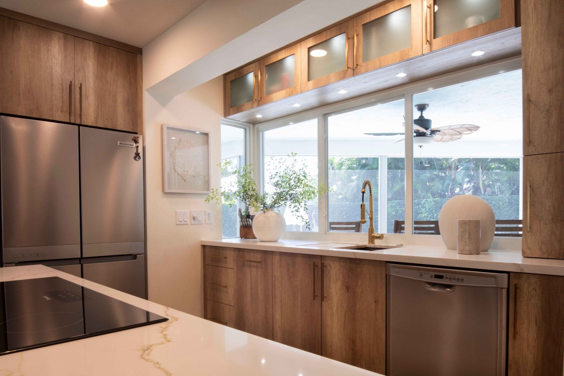 Modern kitchen with wood cabinets, stainless steel appliances, and a large window over the sink.