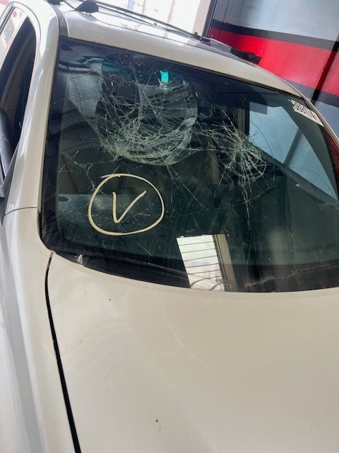 White car with shattered windshield; a yellow circle with a