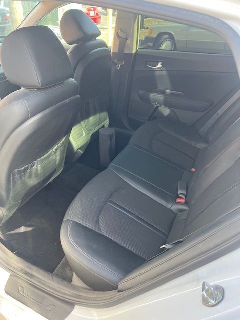Interior of a white Kia Optima showing black leather and cloth rear seats.