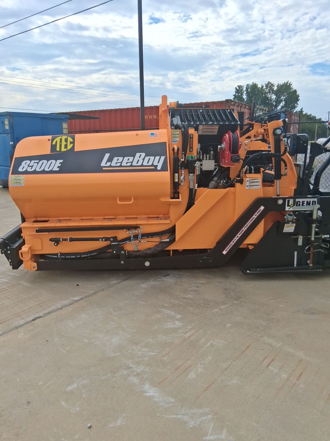 Orange LeeBoy 8500E asphalt paver on a concrete surface, likely a construction site.