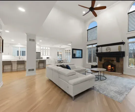 Bright open living room with white sectional, fireplace, hardwood floors, and arched windows.