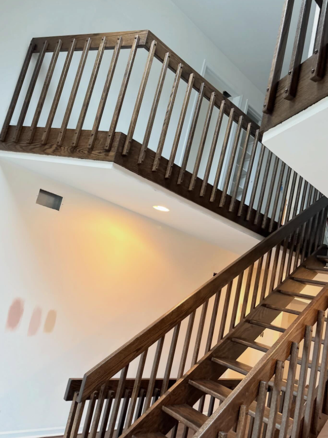 Staircase with dark wood railings and white walls in a bright interior foyer