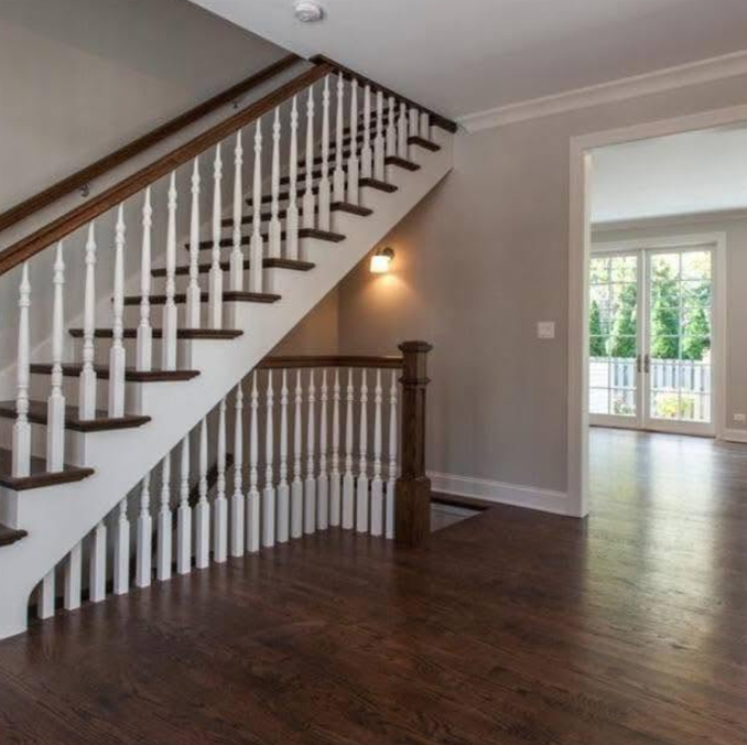 Empty living room with dark wood floors and a staircase with white balusters and wood handrail