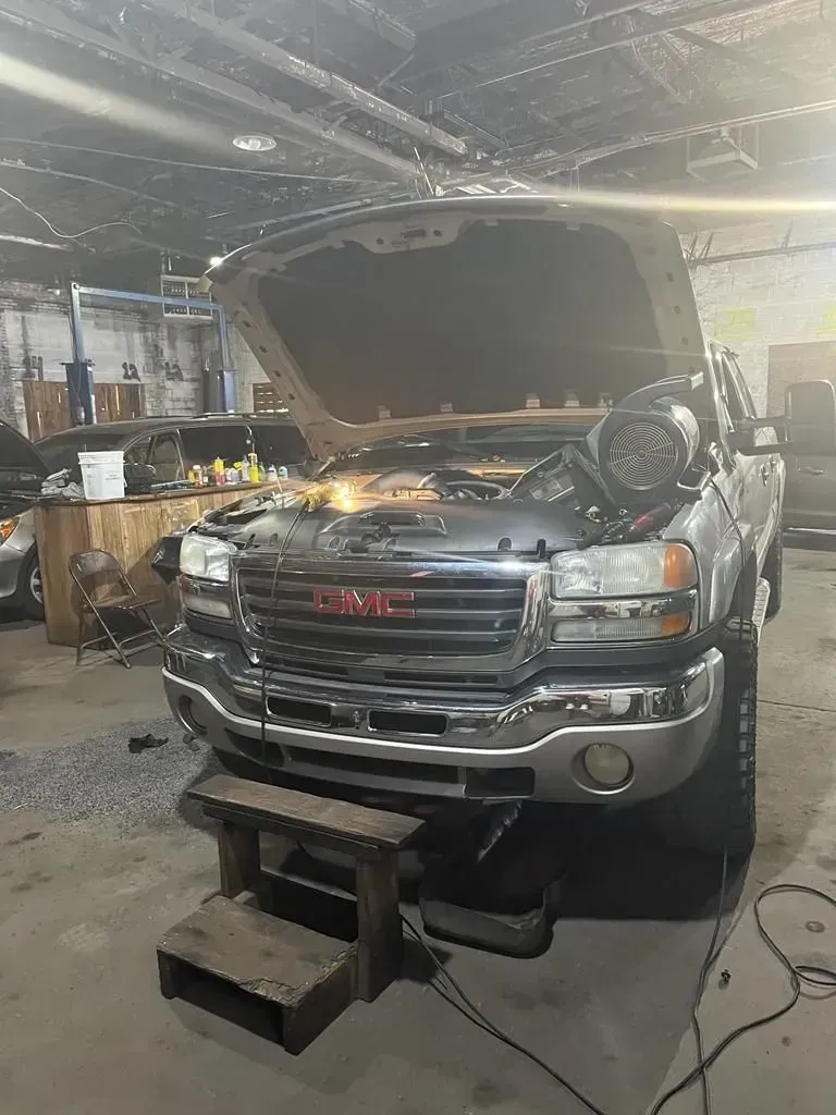 Silver GMC truck in a garage with the hood open.