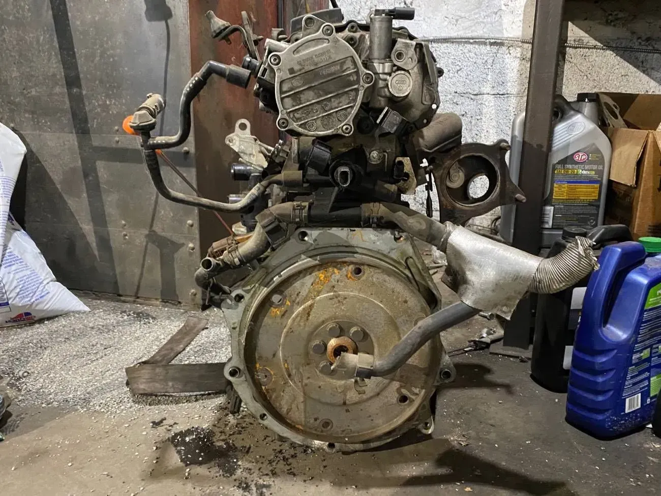 Car engine, mostly metal and some plastic components, in a garage setting.