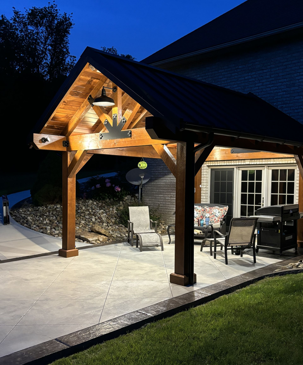 White gazebo with arched openings and benches, on a brick floor, in a sunny garden.
