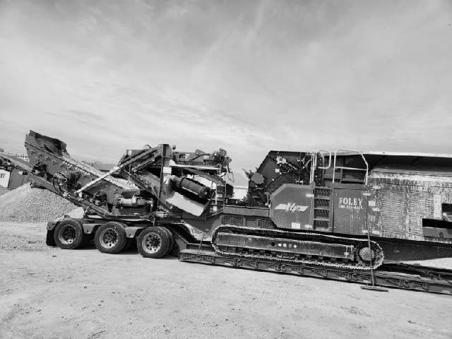A black and white photo of a large machine on a trailer.