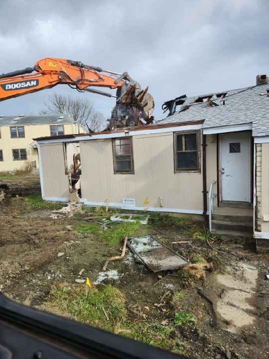 A house is being demolished by a crane.
