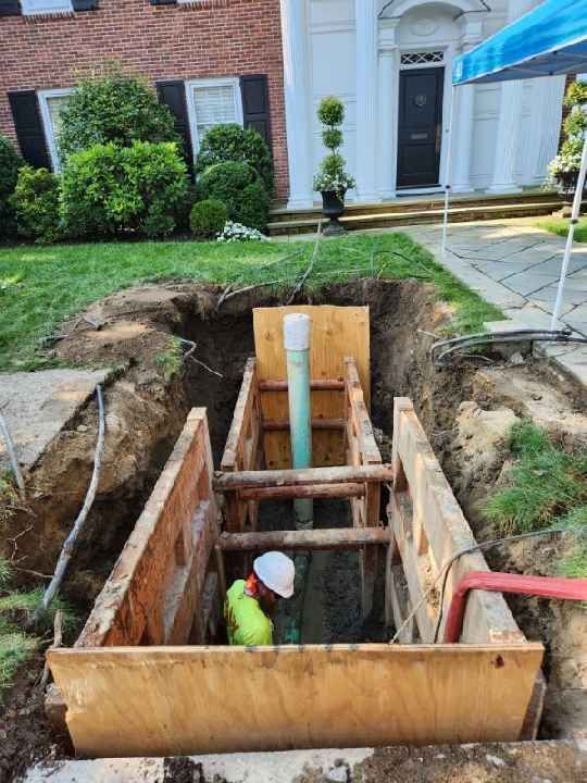 A man is standing in a hole in the ground in front of a house.