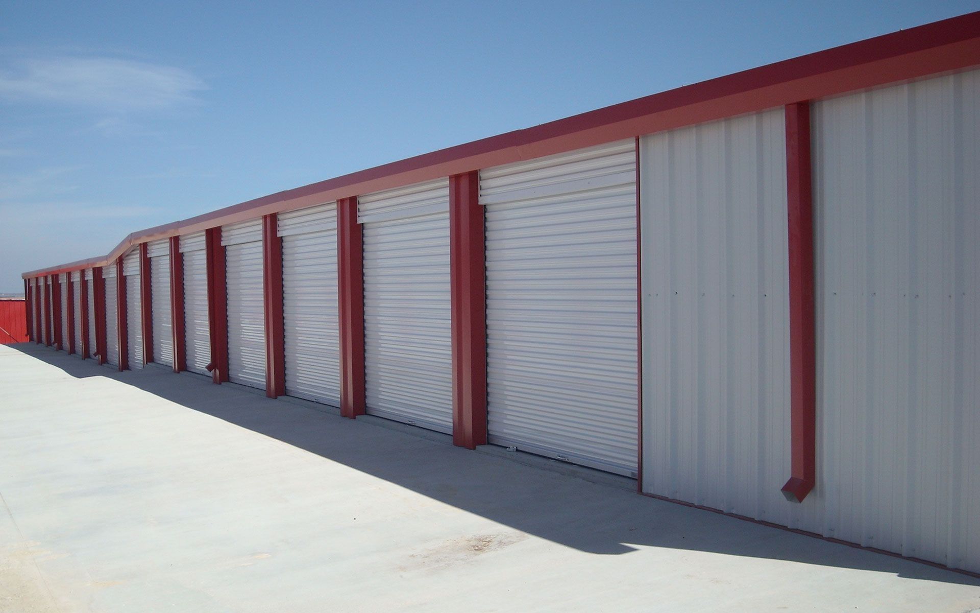 Row of white storage units with red trim under a blue sky.