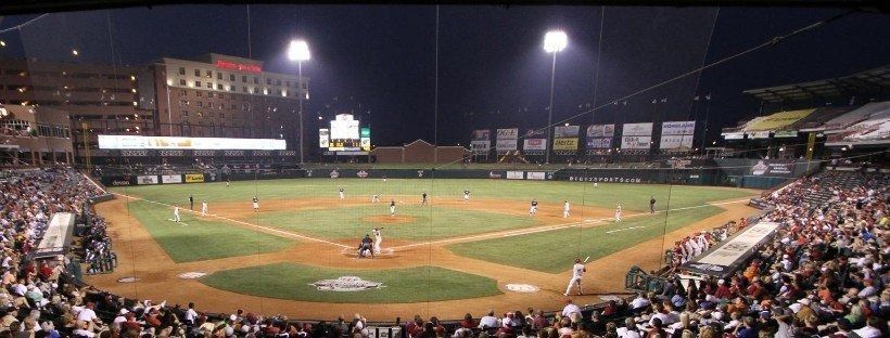 Baseball game at night, players on field, stadium lights, crowd in the stands.